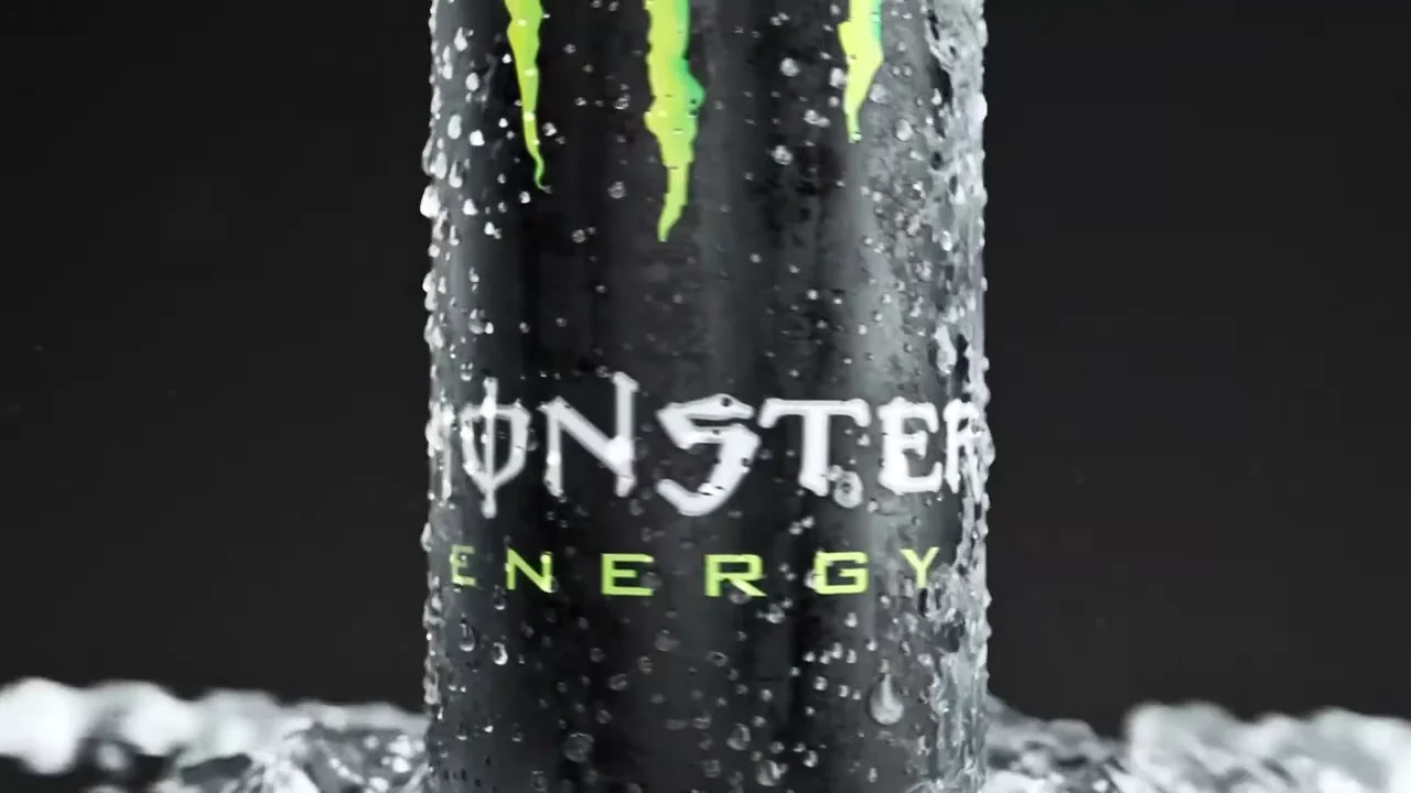 Extreme close-up of the green claw mark and the MONSTER ENERGY wordmark on the wet black can
